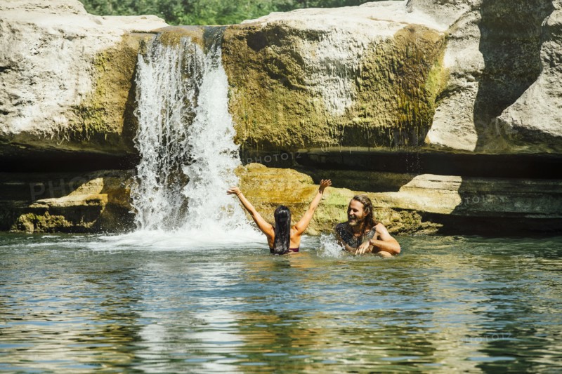 Caucasian couple swimming near waterfall