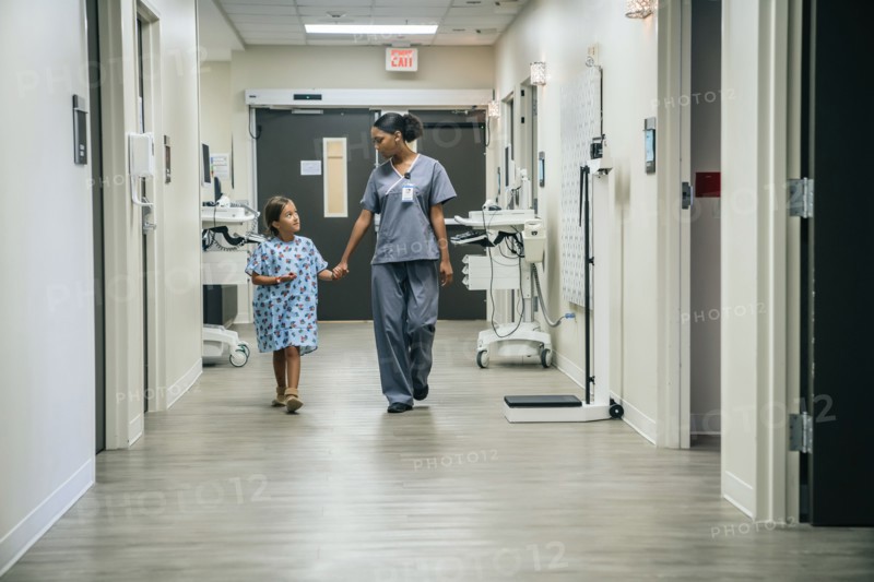 Nurse holding hands with girl in hospital