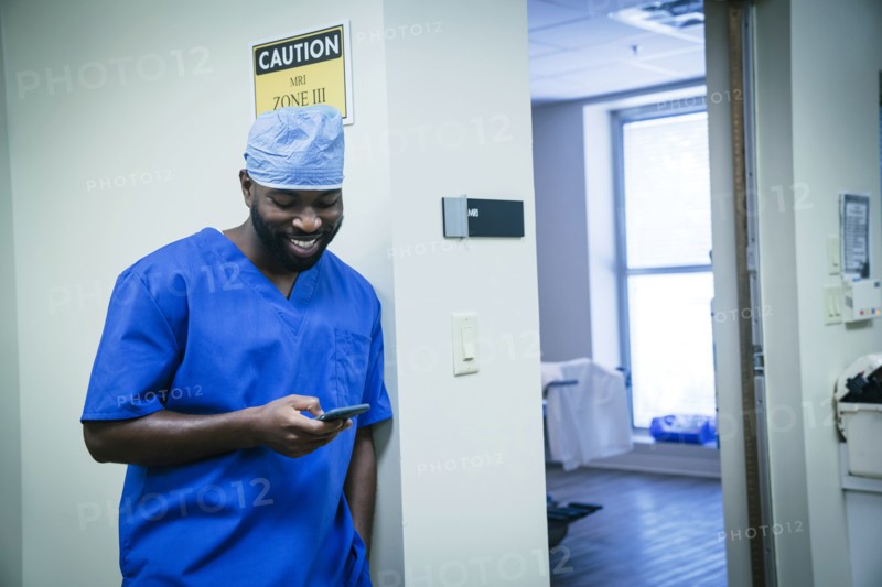 Smiling black nurse texting on cell phone