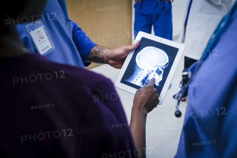 Doctors examining x-ray of skull and jaw on digital tablet