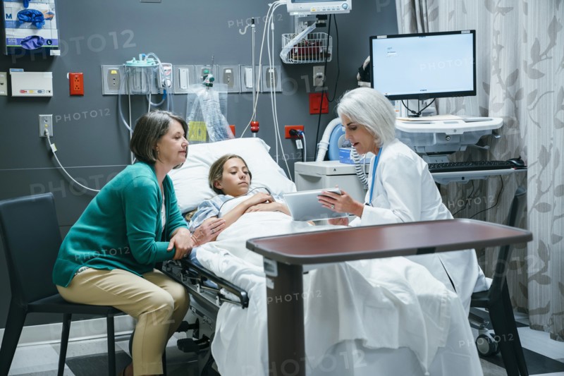 Caucasian doctor with digital tablet talking to mother and daughter in hospital