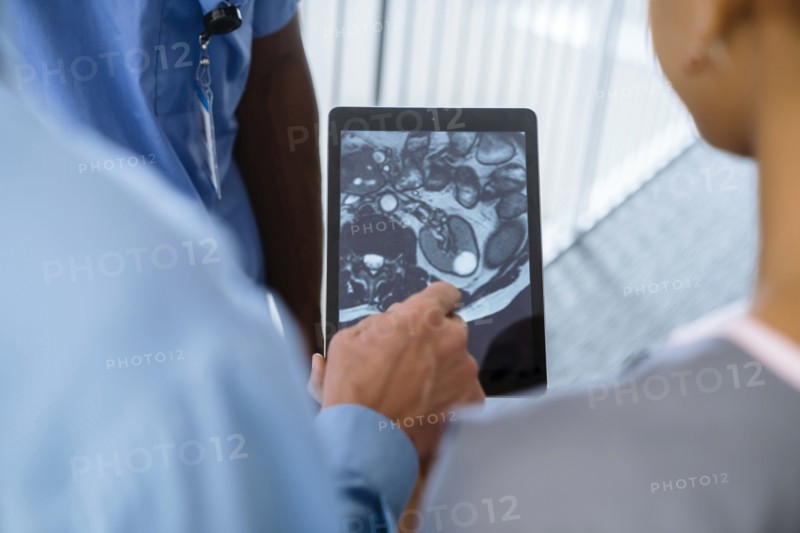 Close up of doctor and nurses viewing image on digital tablet