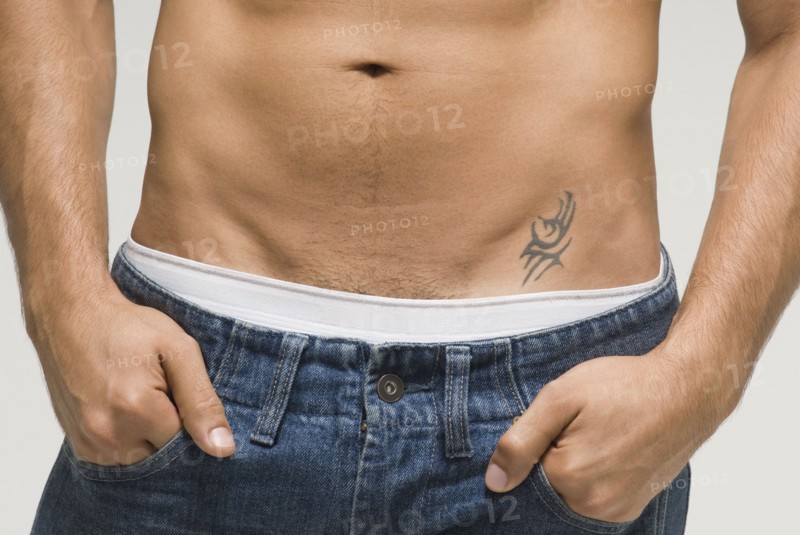 Bare-chested Hispanic man with hands in pockets