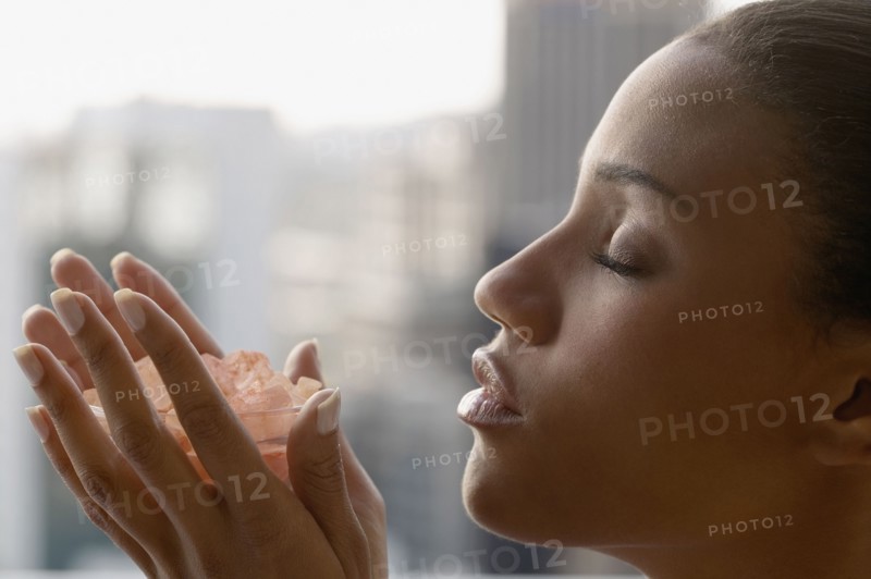 African woman with eyes closed holding bowl of crystals