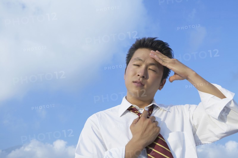 Asian businessman rubbing forehead