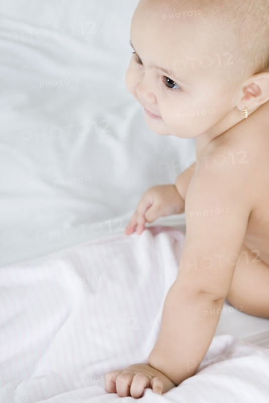 Hispanic baby sitting on bed