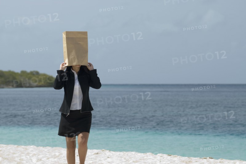 Hispanic businesswoman wearing bag over head