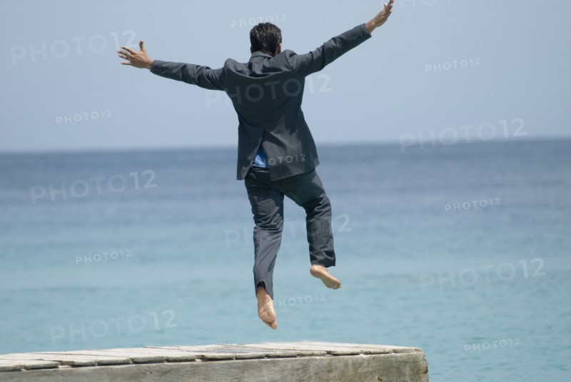 Hispanic businessman jumping off dock