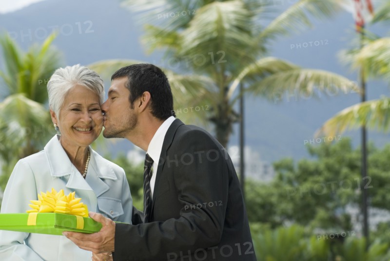 Hispanic man giving gift to mother