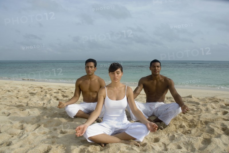 Multi-ethnic friends meditating on beach