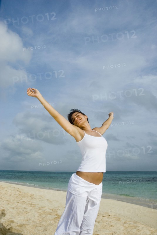 Woman with arms raised at beach