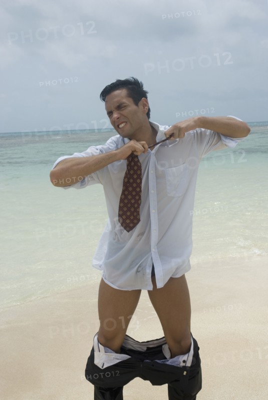 Hispanic businessman stripping at beach