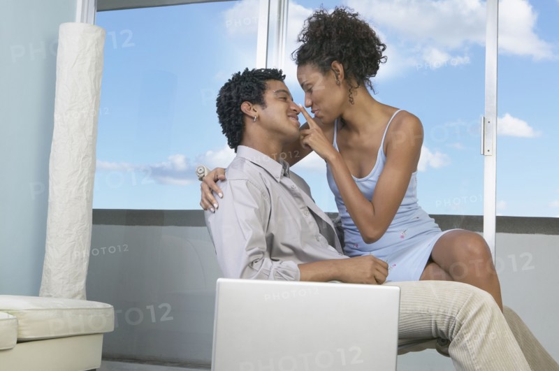 African woman sitting on boyfriend's lap