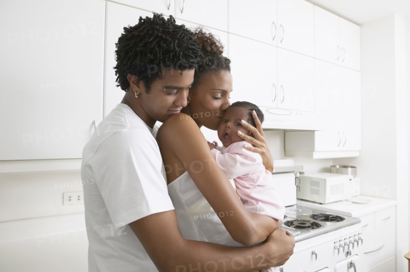African parents hugging baby in kitchen
