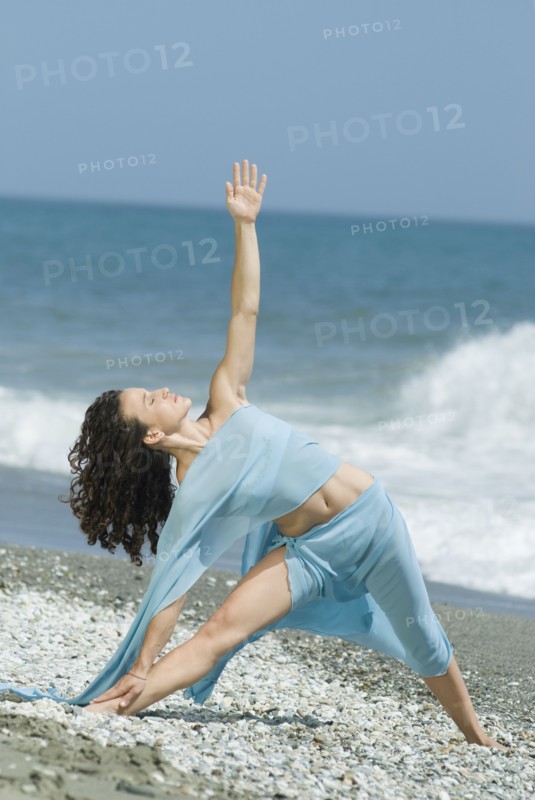 Hispanic woman doing yoga at beach
