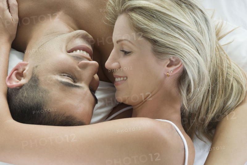 Smiling Hispanic couple laying in bed