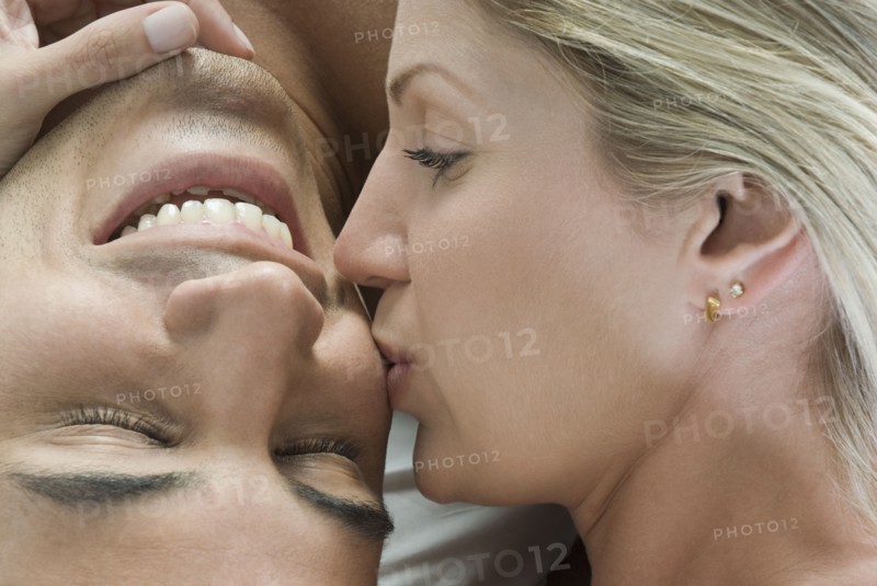 Hispanic woman kissing boyfriend in bed