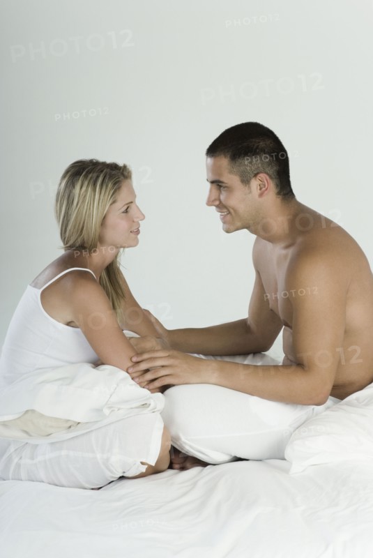 Smiling Hispanic couple sitting in bed