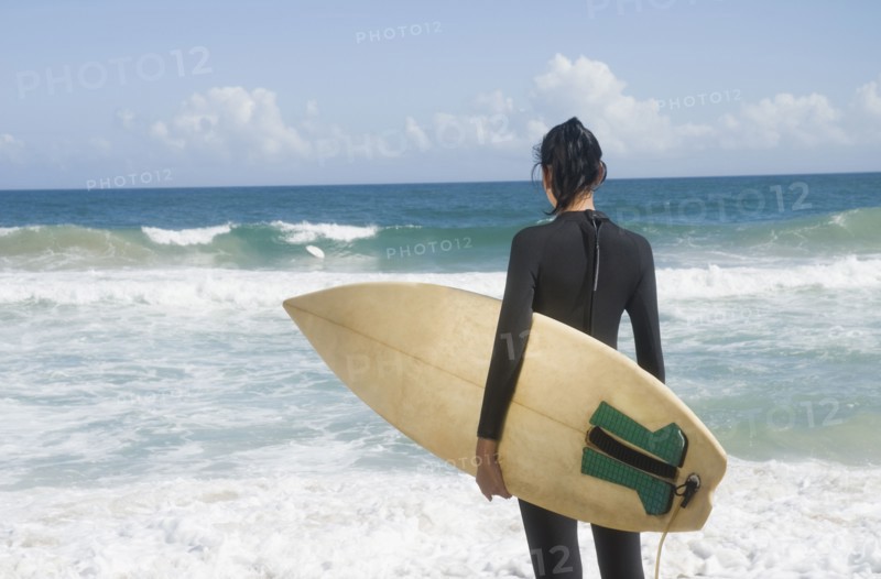 Hispanic woman at beach with surfboard