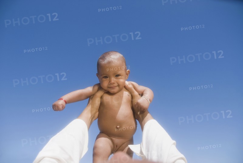 African man lifting nude baby girl