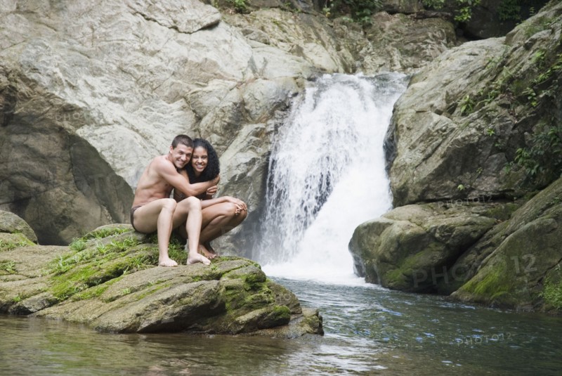 Couple swimming in pool near waterfall