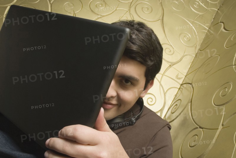 Hispanic man hiding behind laptop