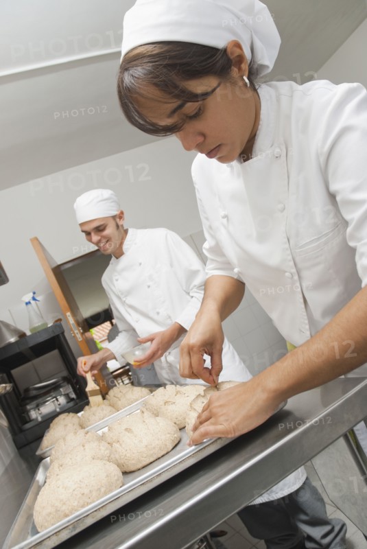 Bakers working with dough in bakery kitchen