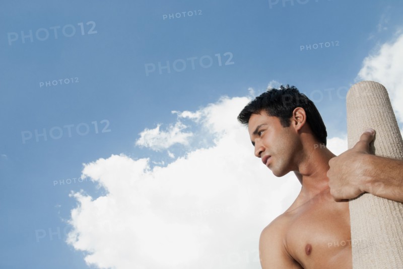 Serious Hispanic man carrying yoga mat