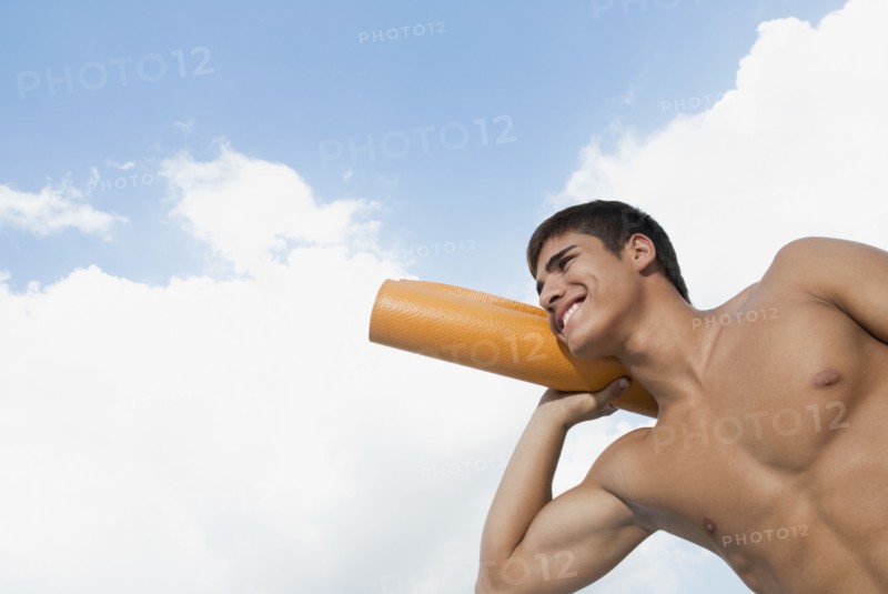Smiling Hispanic man carrying yoga mat