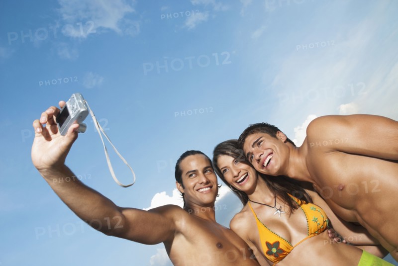 Friends in bathing suits taking self-portrait with digital camera