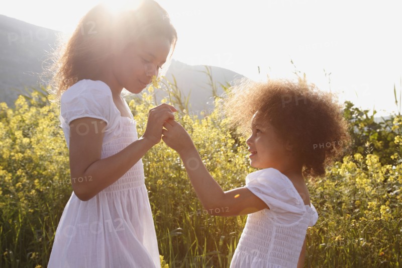 Mixed race girls smelling flowers