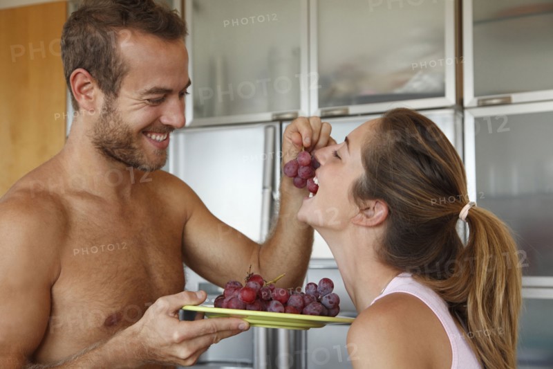 Caucasian man feeding wife grapes
