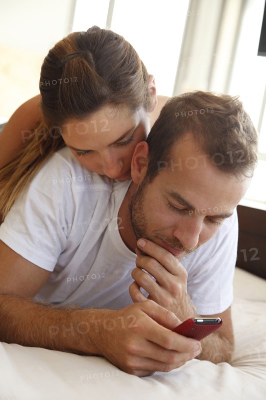 Caucasian woman watching husband using cell phone