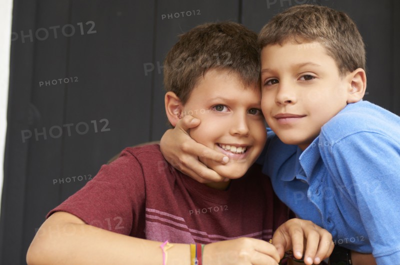Smiling Hispanic boys hugging