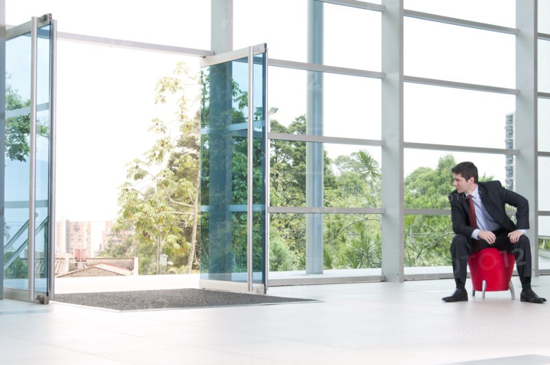 Hispanic businessman sitting on bench in lobby