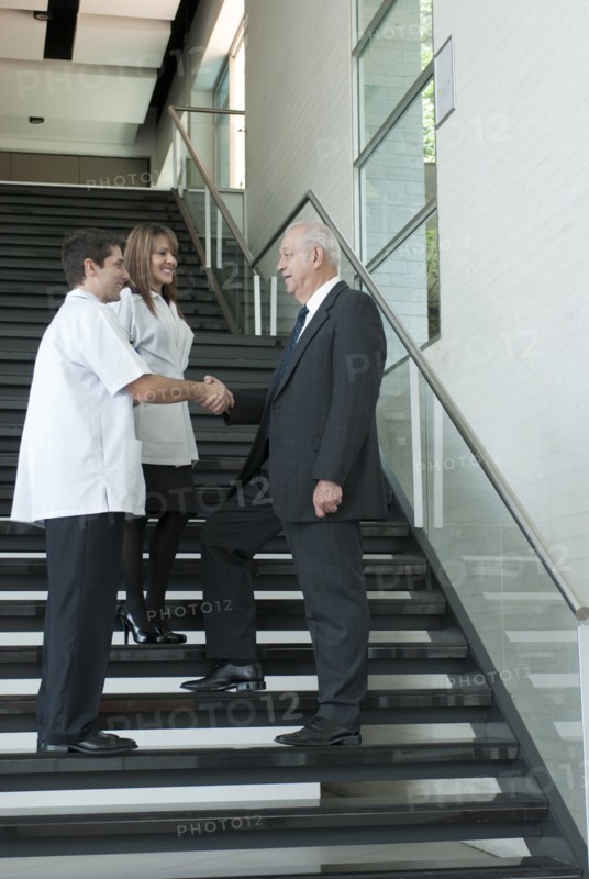 Hispanic businessman shaking hands with doctor on staircase