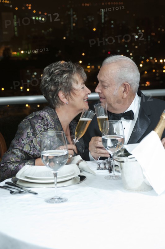 Senior Hispanic couple toasting with Champagne in restaurant