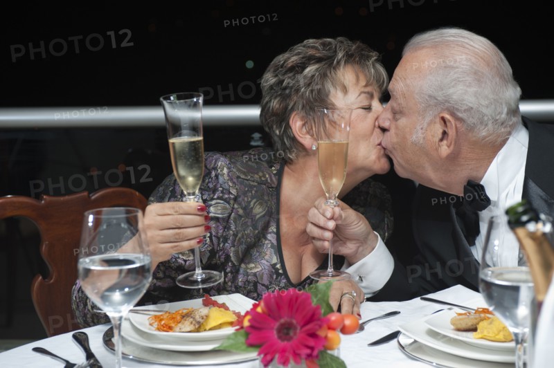 Kissing Hispanic couple toasting with Champagne in restaurant