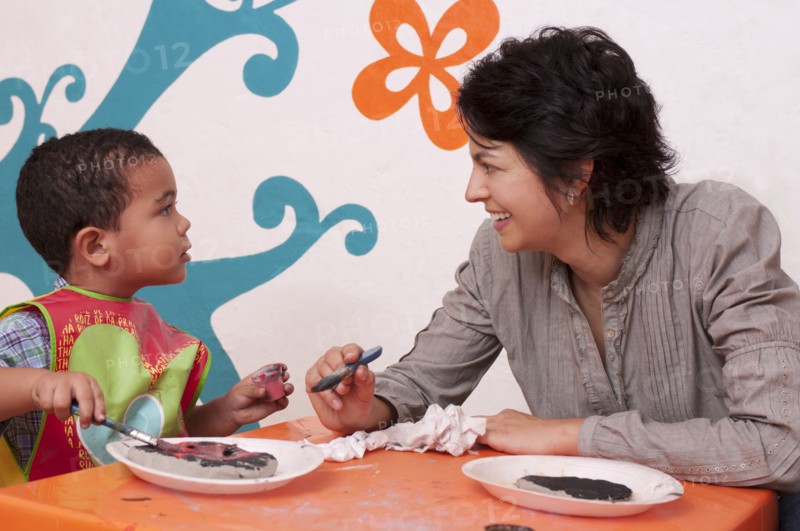 Hispanic mother painting with son