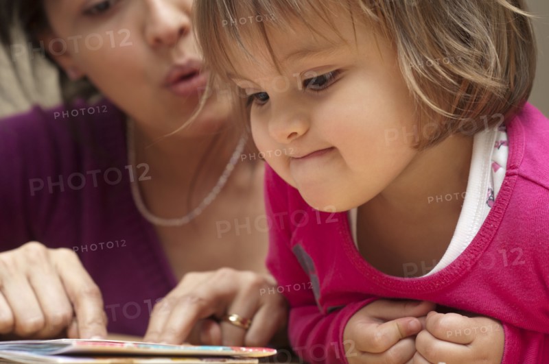 Hispanic mother reading book to daughter