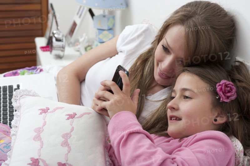 Hispanic mother and daughter looking at cell phone