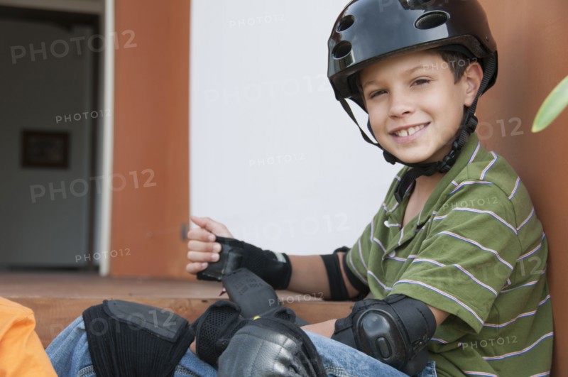 Hispanic boy in skateboard pads and helmet