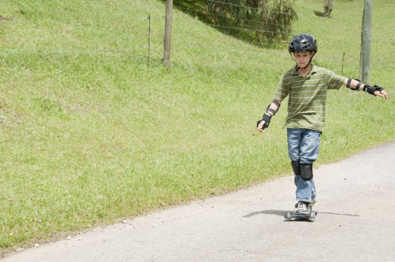 Hispanic boy riding skateboard on road