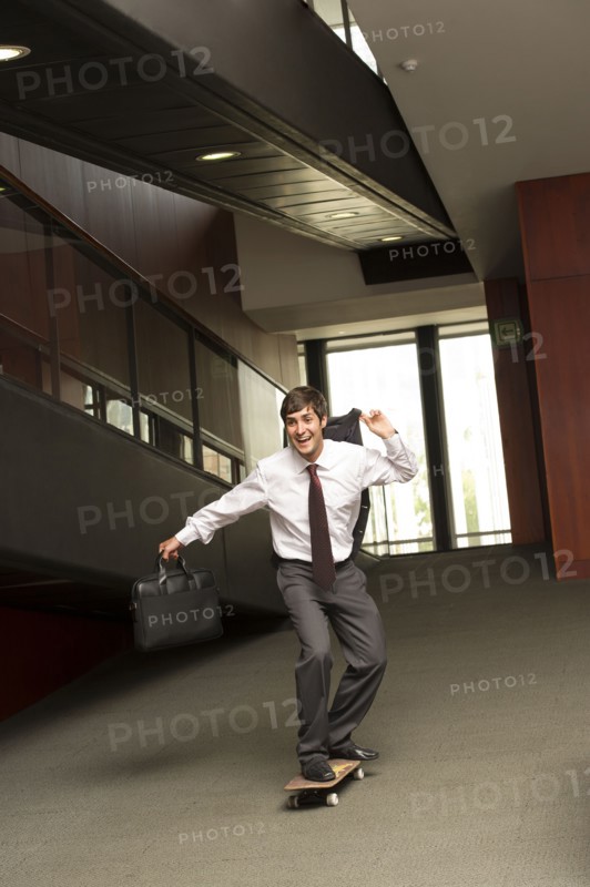 Hispanic businessman riding on skateboard