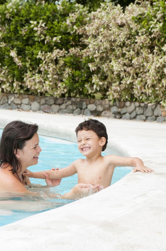 Hispanic mother and son enjoying swimming pool