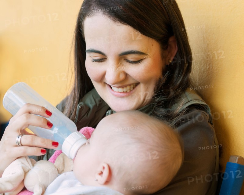 Hispanic mother feeding baby daughter