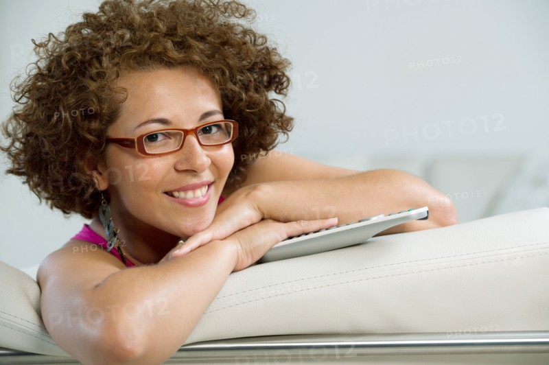 Hispanic woman sitting on sofa with remote control