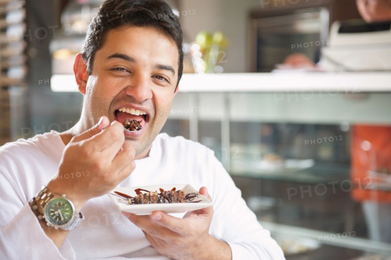 Hispanic man eating dessert in cafe
