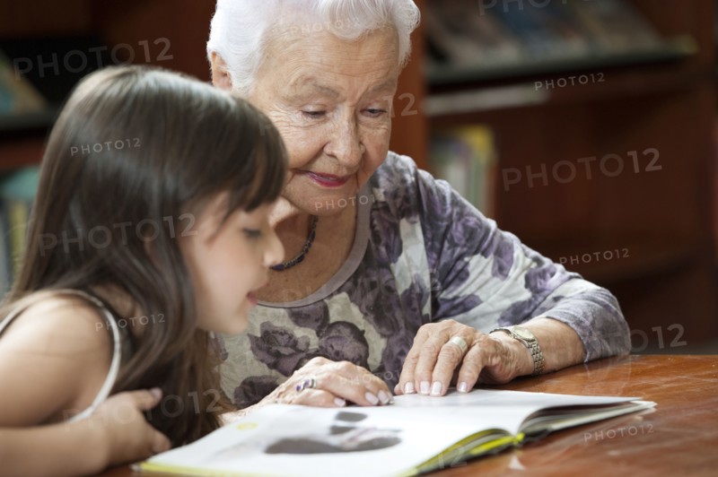 Hispanic grandmother reading book to granddaughter