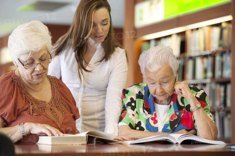 Hispanic teacher helping senior students in library